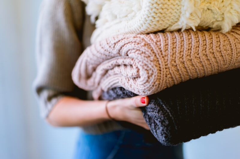 Woman's arm holding a stack of folded sweaters